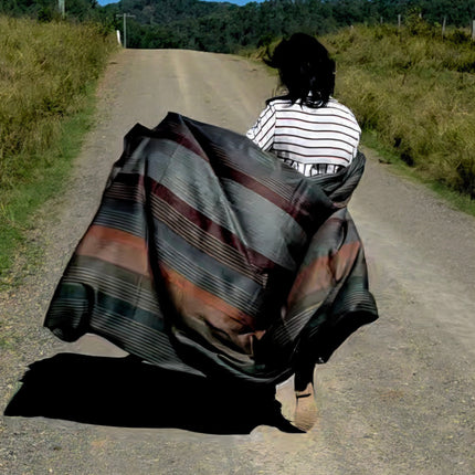 Person walking on a dirt road with a large alpaca wool blanket draped over them