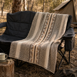 Patterned llama wool throw draped over a camping chair in a Australian bush setting with a tent in the background.