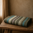 Striped baby alpaca wool blanket on a wooden stool with a neutral background